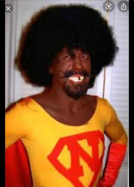 oliver with black face, afro , in a super hero costume with an N on his shirt 